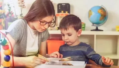 moça-jovem-ensinando-criança-a-ler-e-pintar-atuando-em-seu-trabalho-de-cuidadora-infantil